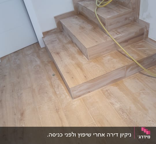 גרם מדרגות וריצוף דמוי עץ מכוסים באבק שיפוץ לפני ניקוי